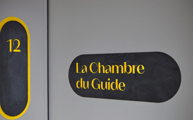 Türschild mit der Aufschrift « La Chambre du Guide » und der Nummer 12 im Hotel Carina Zermatt