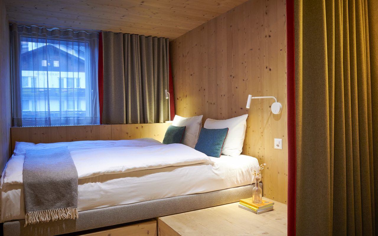 Double Cocoon Zimmer im Hotel Carina Zermatt mit gemütlichem Doppelbett und alpiner Holzverkleidung.