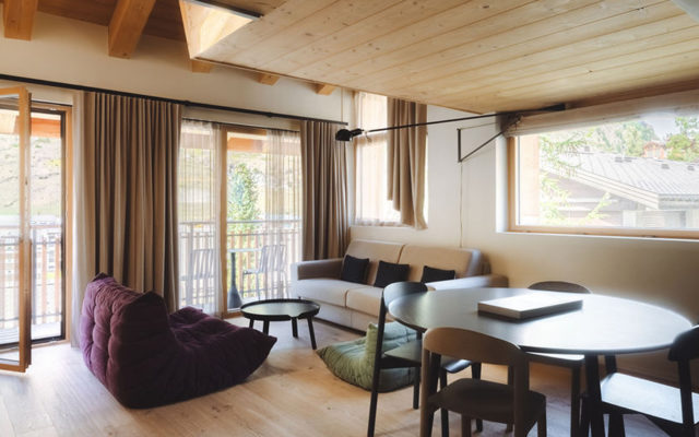 Wohn- und Essbereich des Penthouse Matterhorn im Hotel Carina Zermatt mit Sofa, Esstisch und Balkonzugang