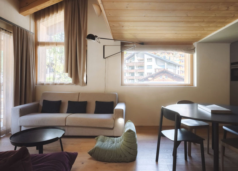 Wohnbereich des Penthouse Matterhorn im Hotel Carina Zermatt mit Sofa und Esstisch