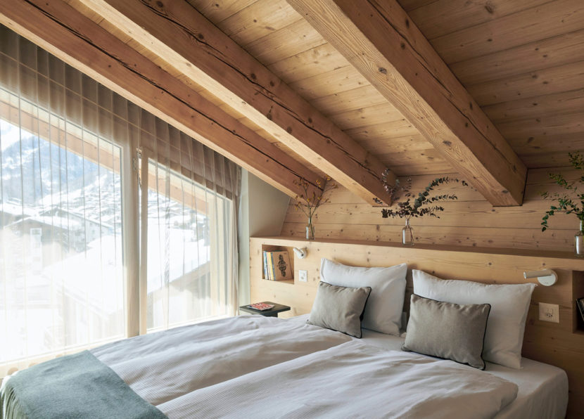 Schlafzimmer des Penthouse Matterhorn im Hotel Carina Zermatt mit Holzdecke und gemütlicher Atmosphäre