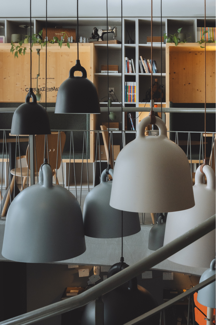 Luminaires design suspendus au-dessus de l’espace commun avec bibliothèque à l’Hôtel Carina Zermatt