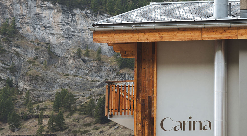 Holzfassade des Hotel Carina Zermatt mit Balkonen vor alpiner Bergkulisse