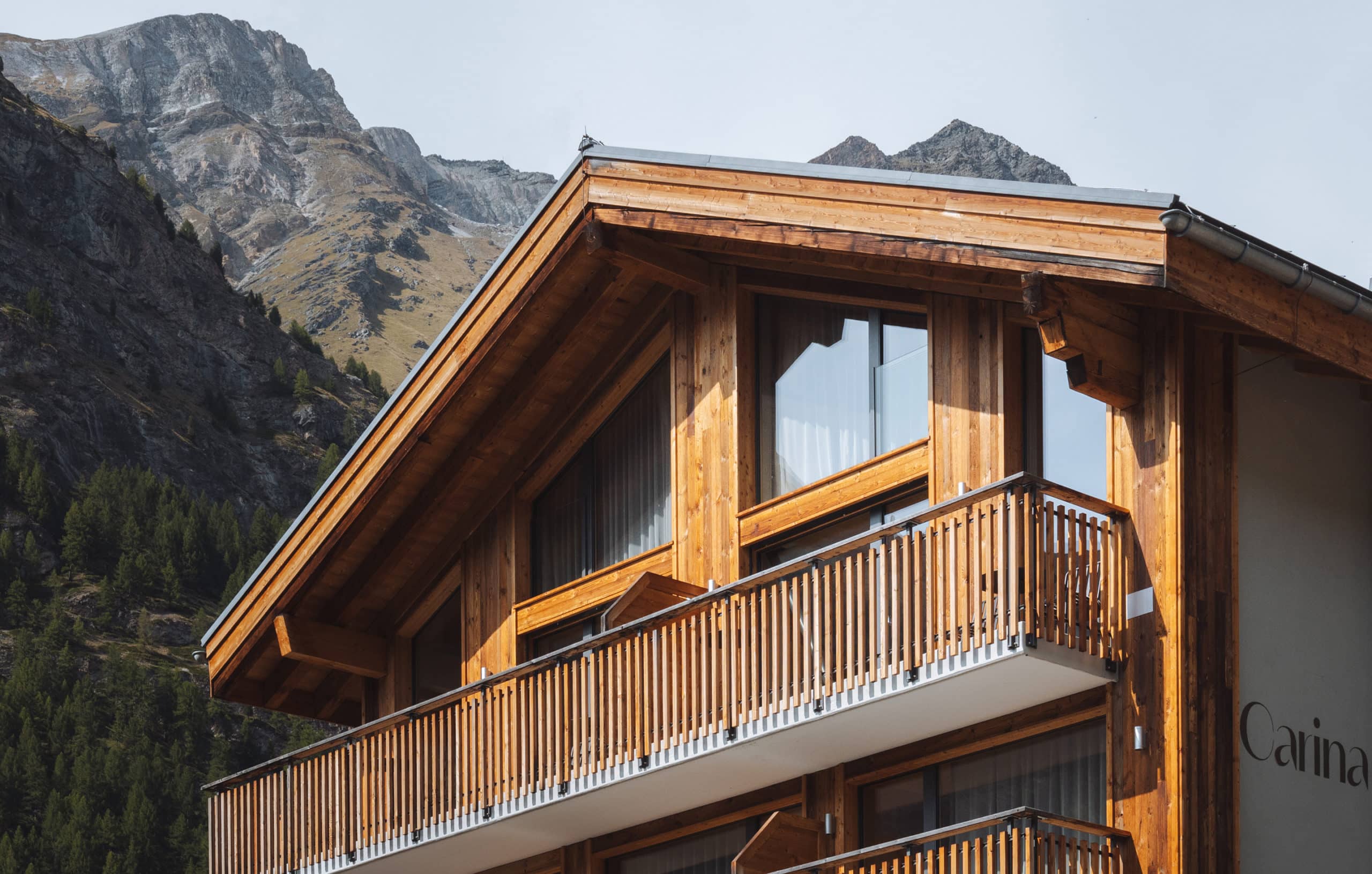 Holzfassade des Hotel Carina in Zermatt mit Balkonen vor felsiger Bergkulisse