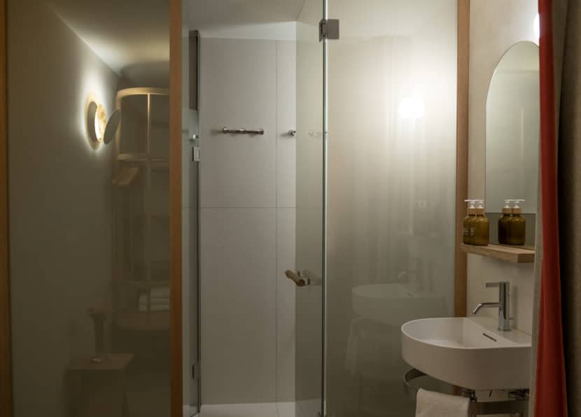 Bathroom of the Chambre du Guide with shower, glass partition and sink.