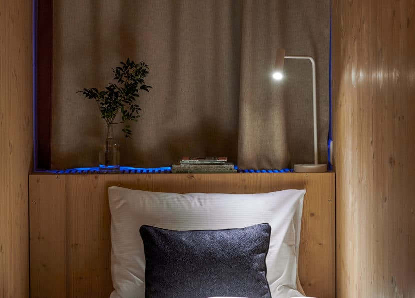 Bed detail in the Chambre du Guide with pillow and wooden paneling.