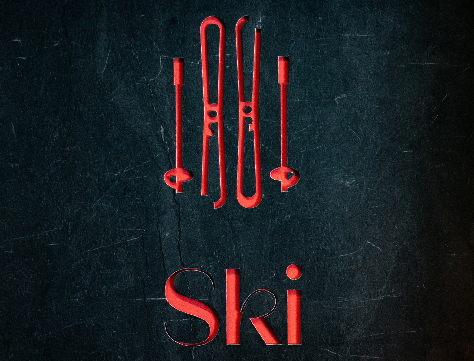 Inscription Ski avec skis rouges en décoration murale sur fond sombre.