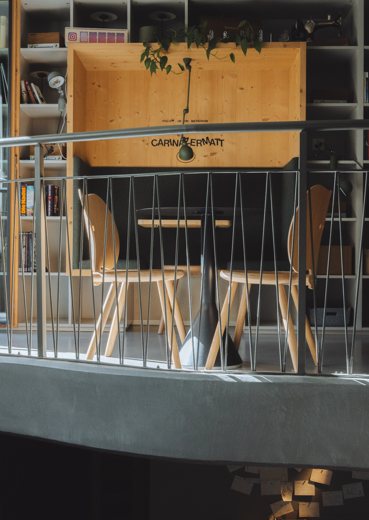 Espace lecture et travail moderne avec habillage en bois, étagères et table avec chaises dans l’espace commun.