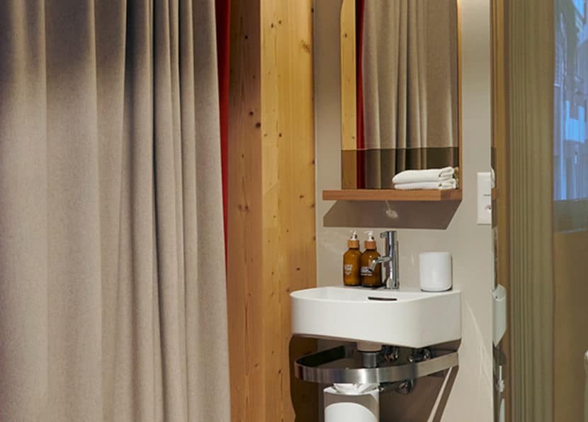 Modern bathroom with sink and mirror in the double room at Hotel Carina Zermatt.