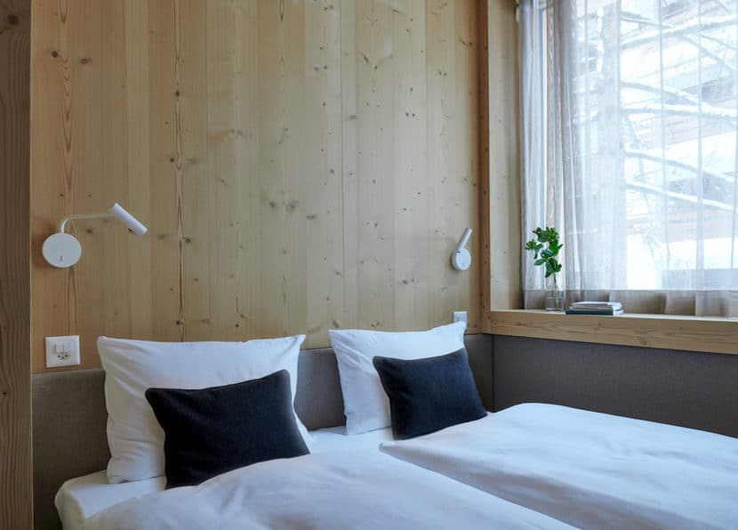 Bright double room with window, wooden walls and cozy bed at Hotel Carina Zermatt.