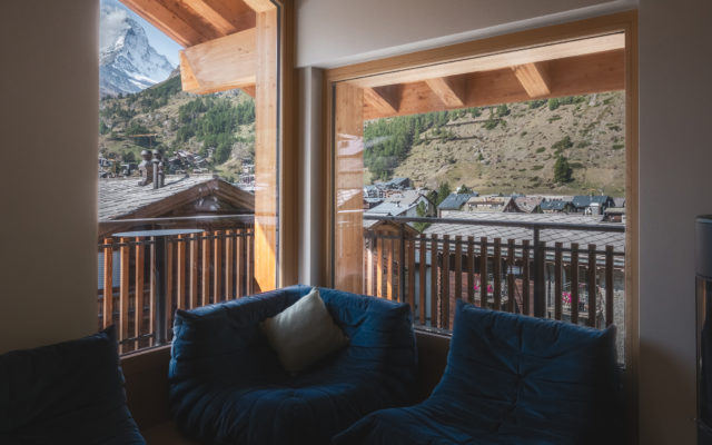 Wohnbereich des Penthouse Matterhorn im Hotel Carina Zermatt mit Sitzgelegenheiten und Balkonzugang