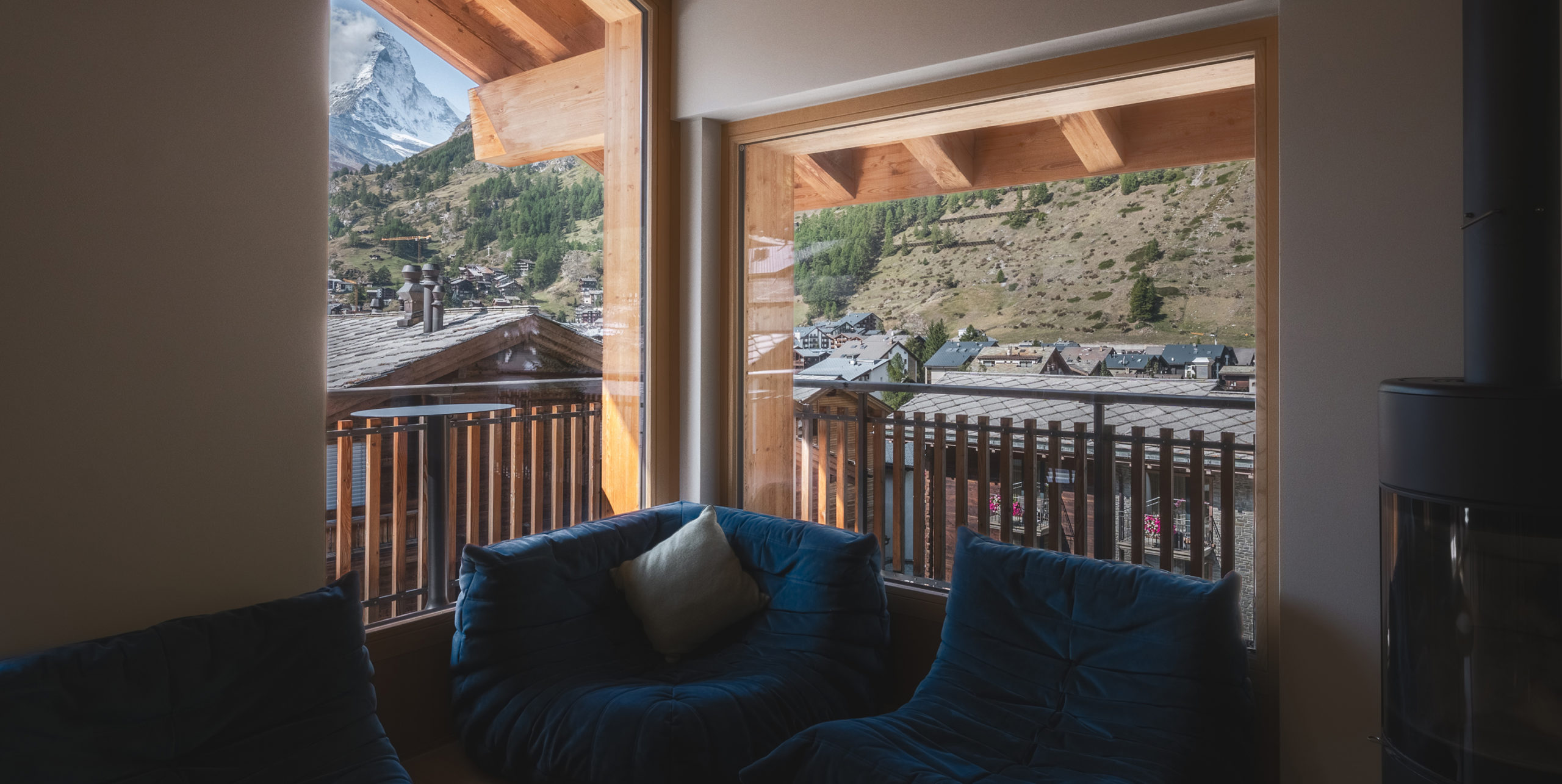 Wohnbereich des Penthouse Matterhorn im Hotel Carina Zermatt mit Sitzgelegenheiten und Balkonzugang