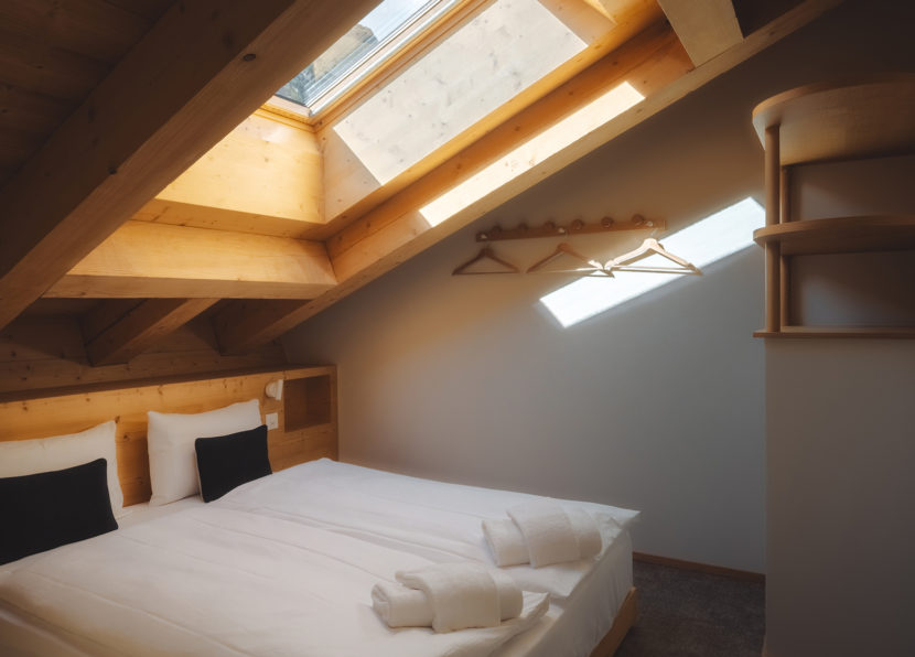 Chambre du Penthouse Matterhorn à l’Hôtel Carina Zermatt avec lit double et fenêtre de toit