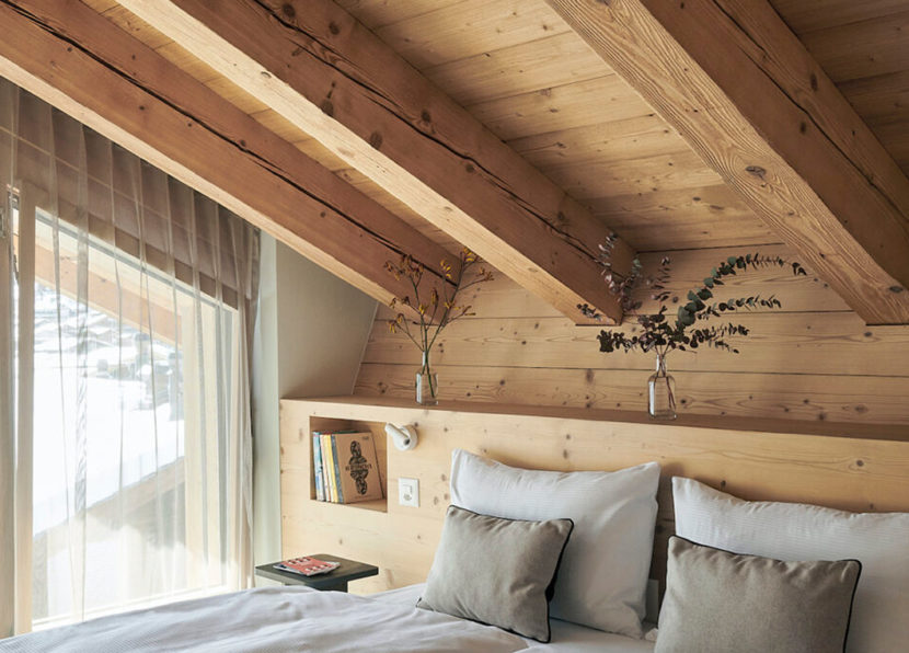 Chambre du Penthouse Matterhorn à l’Hôtel Carina Zermatt avec plafond en bois et détails décoratifs