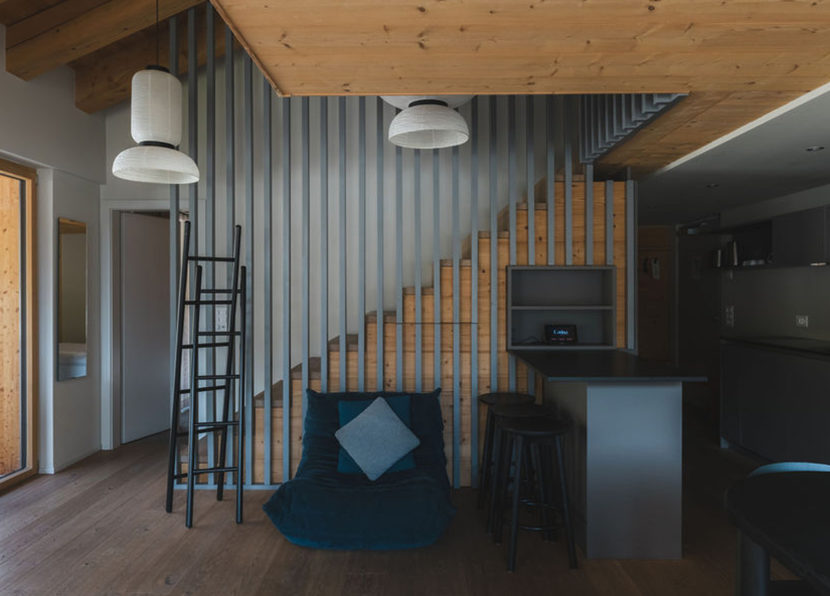 Wohnbereich des Penthouse Matterhorn im Hotel Carina Zermatt mit Treppe, Sitzbereich und Küchenbar