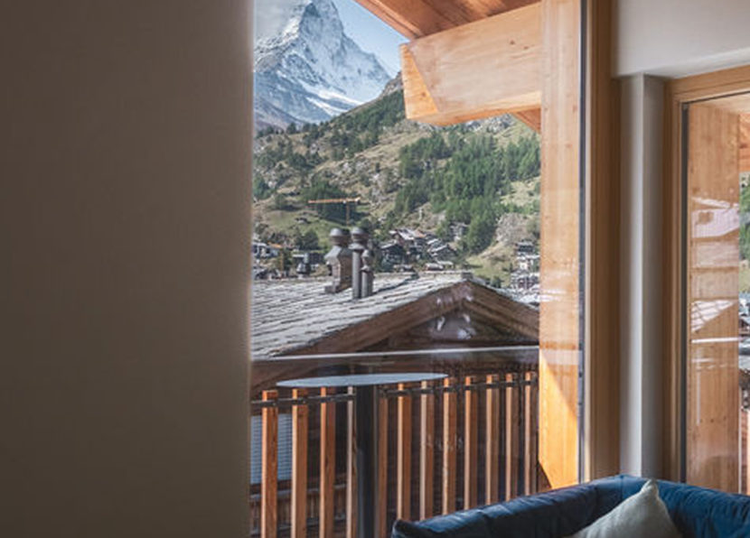 Vue sur le Cervin depuis l’espace salon du Penthouse Matterhorn à l’Hôtel Carina Zermatt à travers la fenêtre