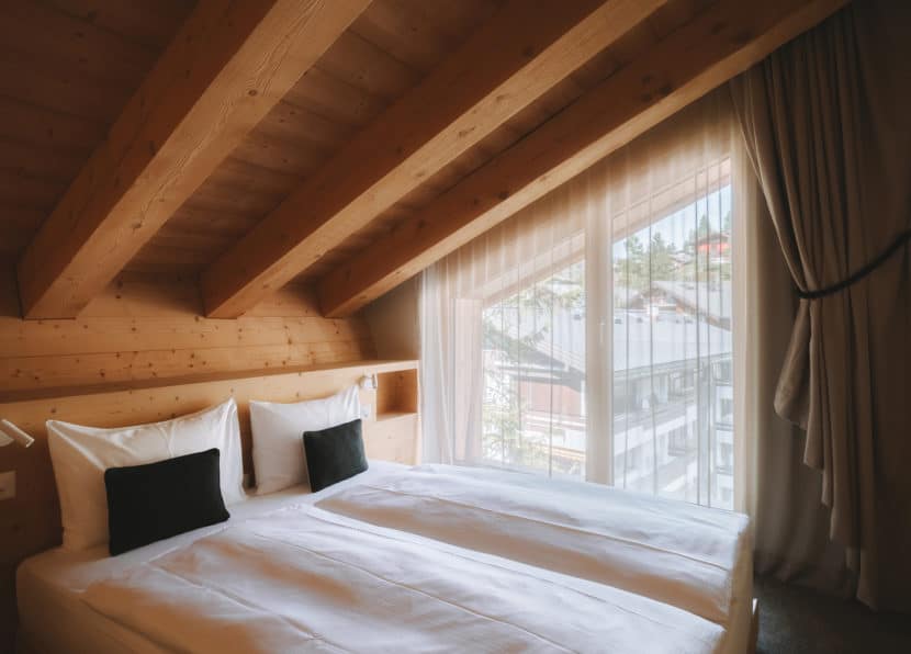 Schlafzimmer des Penthouse Matterhorn im Hotel Carina Zermatt mit Doppelbett und Fenster