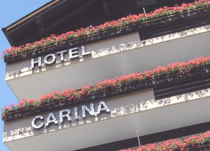 Historic facade of Hotel Carina with flower-lined balconies