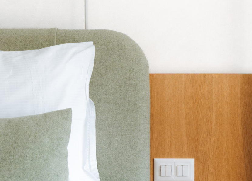 Close-up of a bed with upholstered headboard and light switches