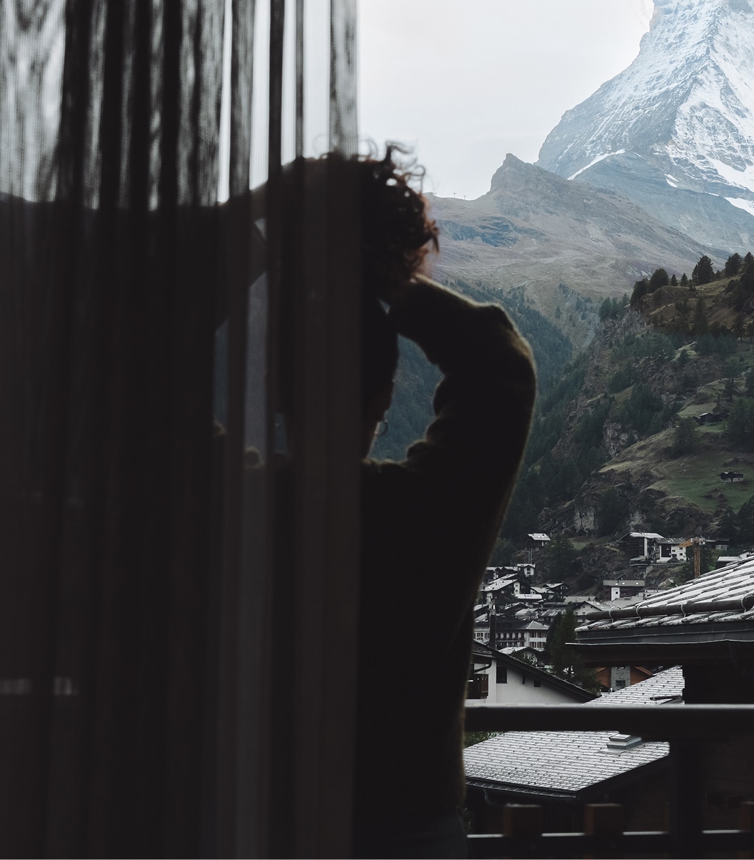 Person steht auf einem Balkon und blickt auf das Matterhorn und das Dorf Zermatt