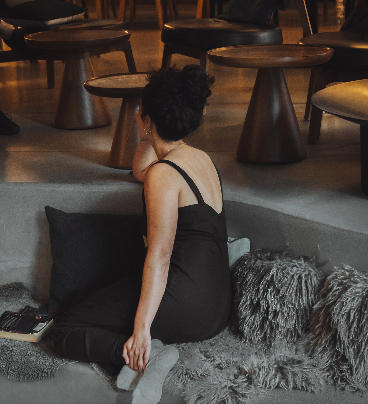 Personne assise dans l’espace lounge de l’Hôtel Carina Zermatt avec tables basses et coussins