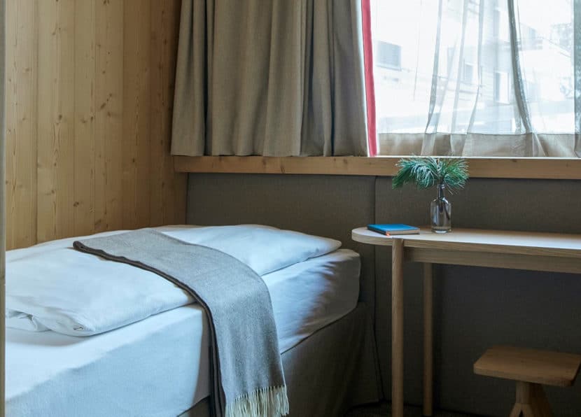 Twin room with single bed, window and seating bench at Hotel Carina Zermatt.